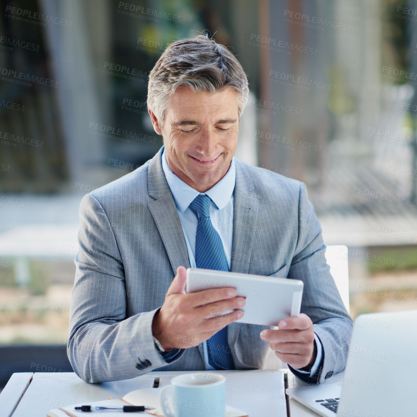 Buy stock photo Shot of a mature businessman sitting outside using a digital tablet