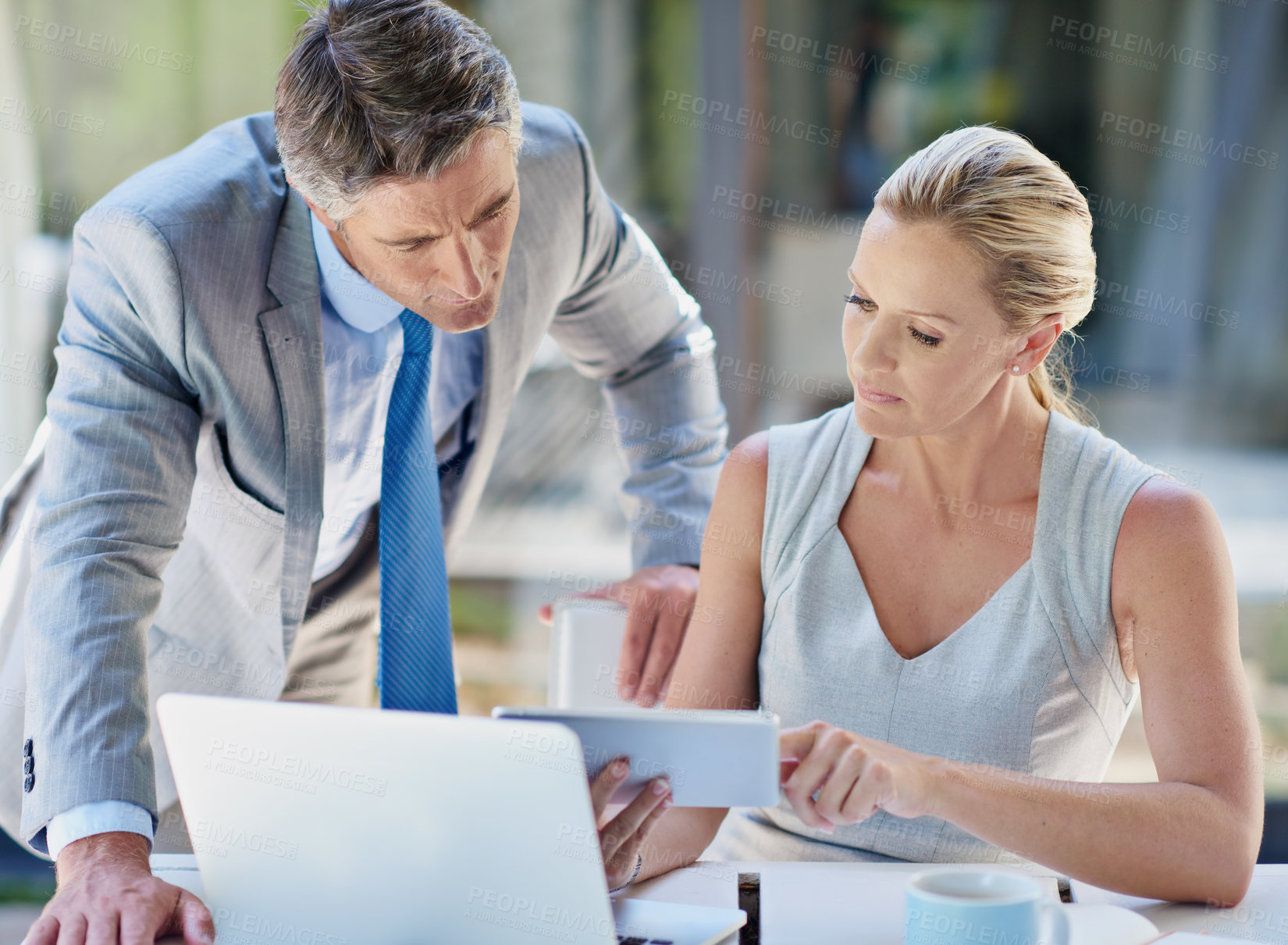 Buy stock photo Shot of two mature businesspeople talking together of a tablet and laptop