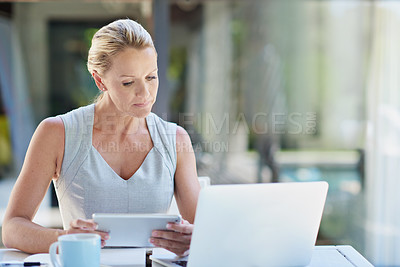 Buy stock photo Shot of a mature businesswoman working with a tablet and a laptop