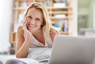 Buy stock photo Portrait of a beautiful mature woman lying on her living room floor using a laptop