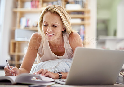 Buy stock photo Shot of a beautiful mature woman lying on her living room floor doing some research