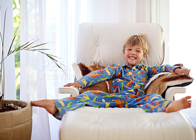 Buy stock photo Boy, portrait and happy on couch, sofa or recliner at home for weekend away, school break or holiday. Child, smile and playful pyjamas on in living room for vacation, relaxing and enjoying morning