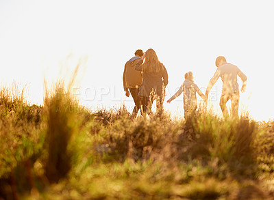 Buy stock photo Family, nature and walk at sunset, bonding and exercise for parents and children. Lens flare, autumn and grass for hike on holiday in English countryside, mother and father for outdoor activity  