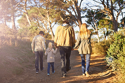 Buy stock photo Rearview shot of a young family walking along a forest trail