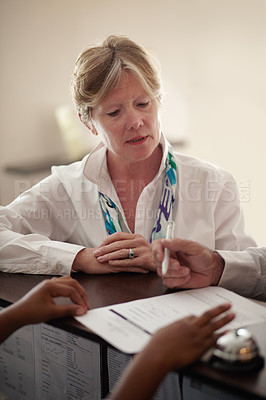 Buy stock photo Senior woman, hotel and signing documents at reception desk for booking, reservation or weekend vacation. Mature person filling forms, application or checking paperwork or sign in at holiday resort