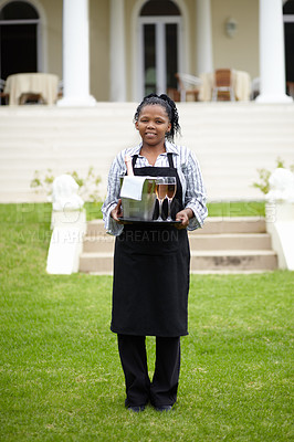 Buy stock photo Black woman, waitress and carrying wine in garden, vinyard or resort in the countryside. Happy African female person with champagne, alcohol or bottle to serve people, reservation or customer service