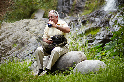 Buy stock photo Senior, man and drinking water in forest for break, sightseeing or vacation with waterfall and scenery. Elderly person in woods or nature to rest on holiday, adventure or experience with backpack