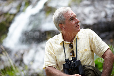 Buy stock photo Senior, man and binocular in forest with looking, sightseeing or vacation with waterfall and scenery. Elderly, man and person in woods or nature for holiday, adventure or experience for leisure