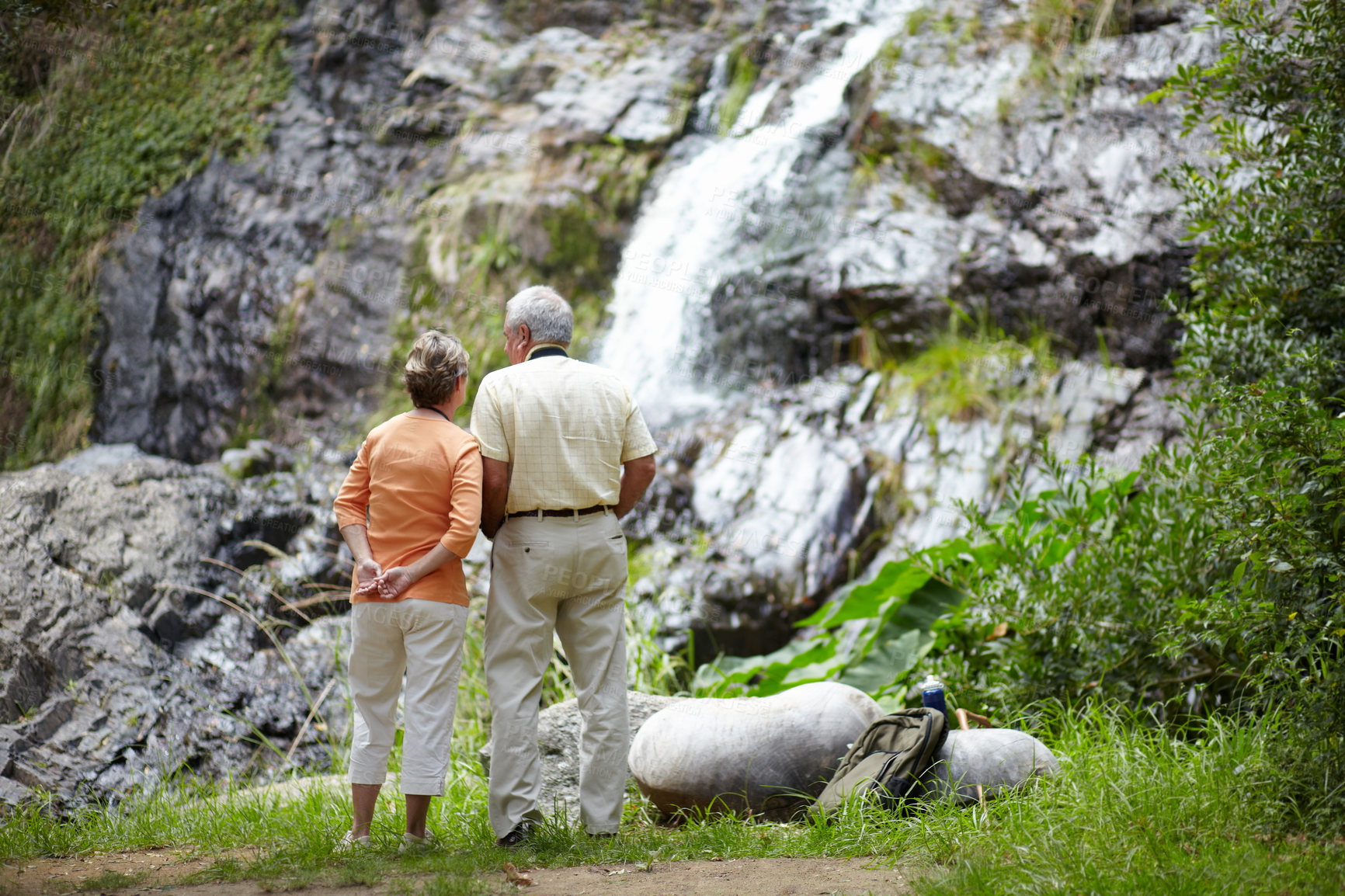 Buy stock photo Back, love and senior couple with vacation, waterfall and nature with holiday, romance and relationship. Romantic, outdoor or elderly man with old woman, fresh air or view with break, forest or relax