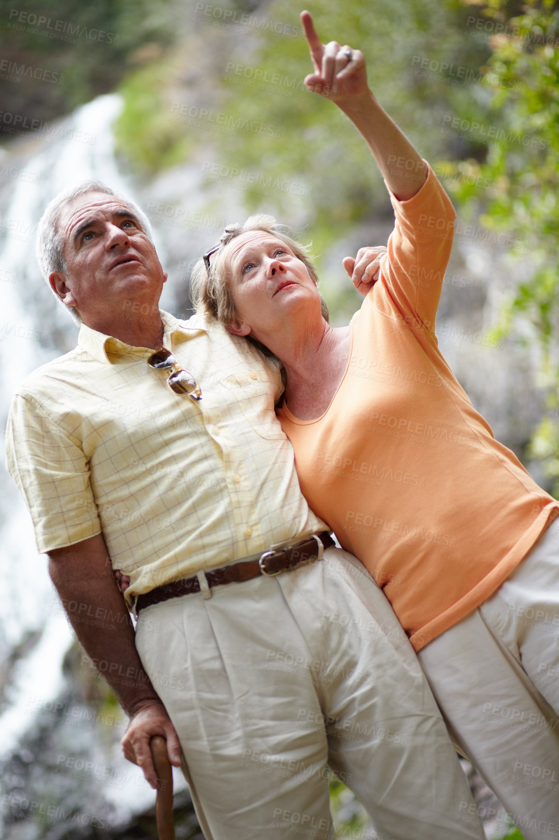 Buy stock photo Senior, man and woman with pointing in forest for travel, sightseeing or holiday with waterfall. Elderly, couple or face and showing view for vacation and adventure on retirement or tourism in nature