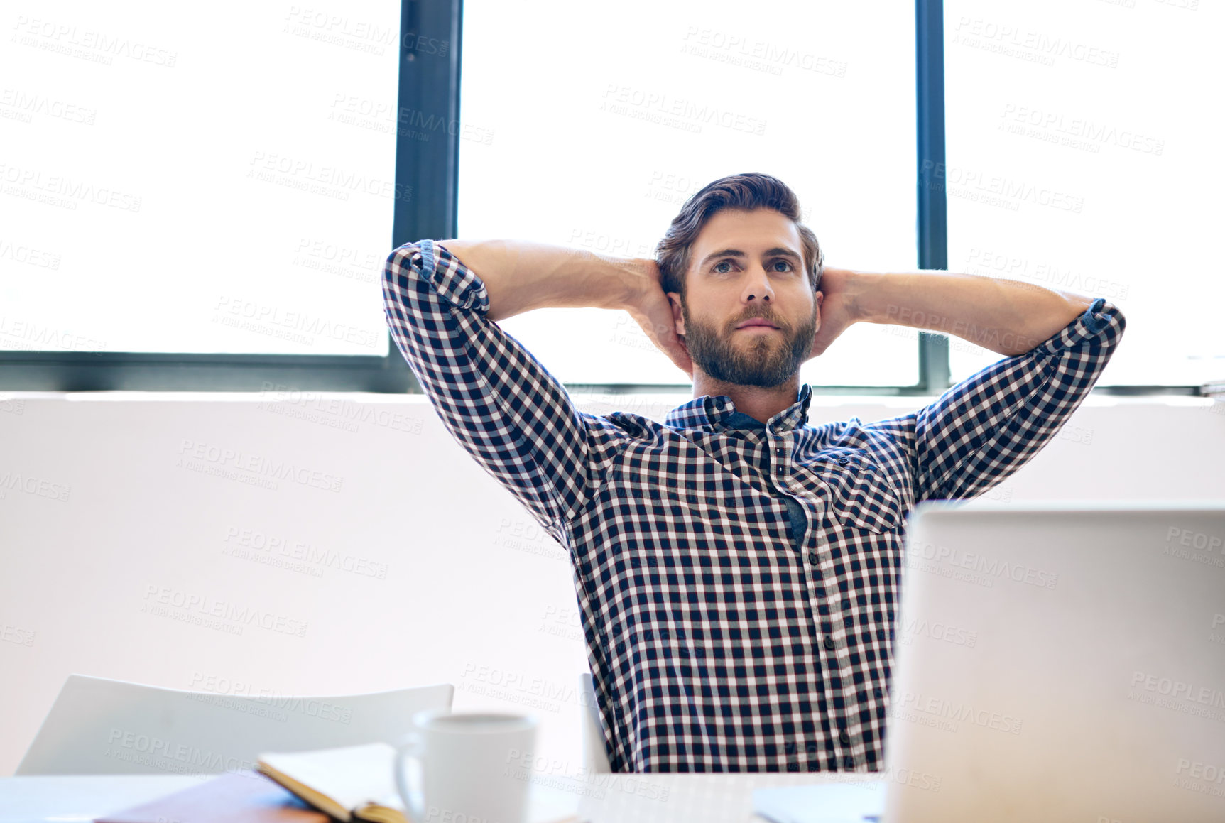 Buy stock photo Shot of a handsome businessman sitting with his hands behind his head at the office