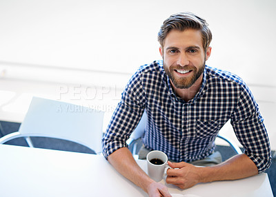 Buy stock photo Portrait of a handsome businessman sitting with a cup of coffee at his office desk