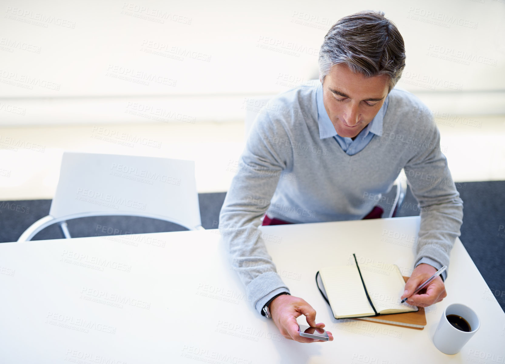 Buy stock photo Businessman, phone and writing with budget book above for schedule planning, reminder or diary notes at office. Top view, man or financial planner with mobile smartphone for finance app or calculator