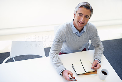 Buy stock photo Portrait of a businessman sitting with his cellphone and notebook at his office desk