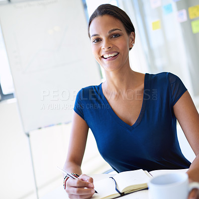Buy stock photo A young businesswoman writing in a notebook while working at her desk