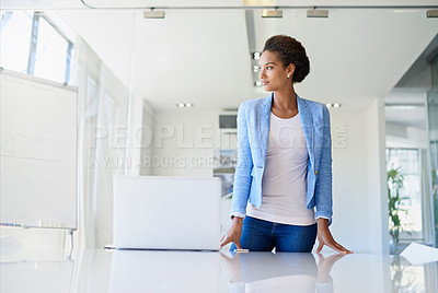 Buy stock photo A young businesswoman at the office standing behind a table with a laptop on it