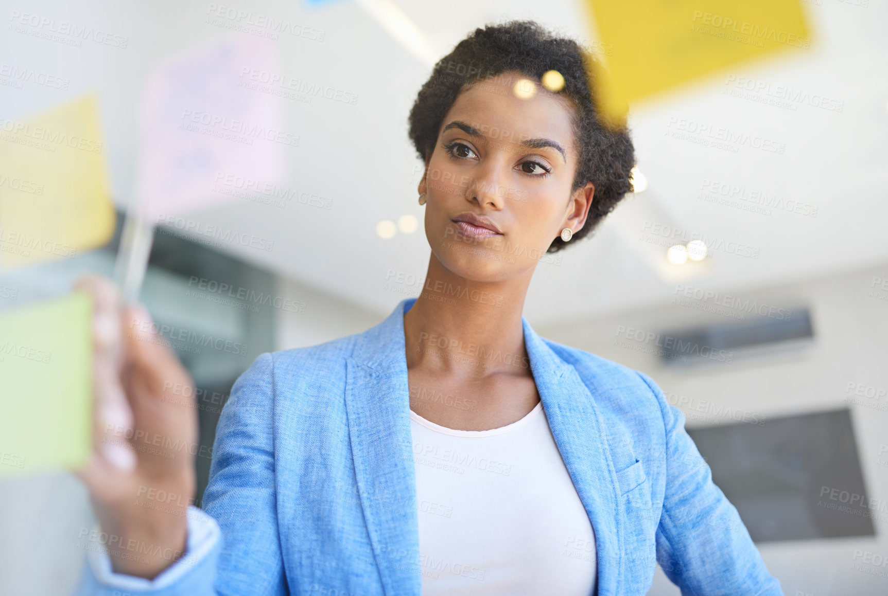 Buy stock photo Shot of a young businesswoman arranging sticky notes on a glass wall while planning