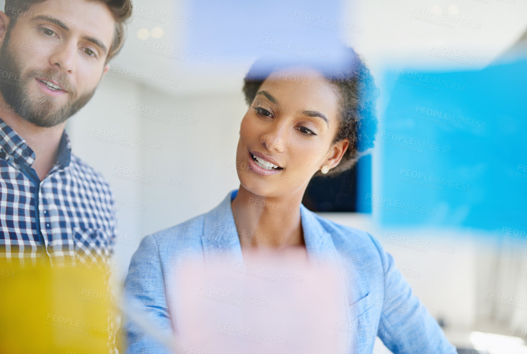 Buy stock photo Shot of coworkers arranging sticky notes on a glass wall during a brainstorming session