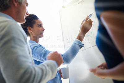 Buy stock photo Shot of a group of coworkers discussing ideas while standing by a whiteboard