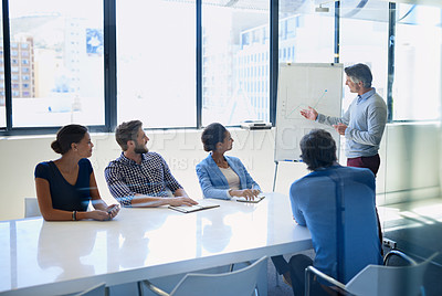 Buy stock photo A businessman doing a presentation using a whiteboard during a boardroom meeting