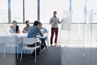 Buy stock photo A businessman doing a presentation using a whiteboard during a boardroom meeting