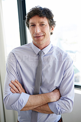 Buy stock photo Portrait of a businessman standing with his arms crossed by his office window