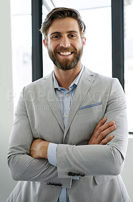Buy stock photo Portrait of a confident young businessman standing with his arms crossed in his office