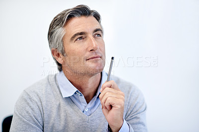 Buy stock photo Shot of a mature businessman holding his pen and looking thoughtful