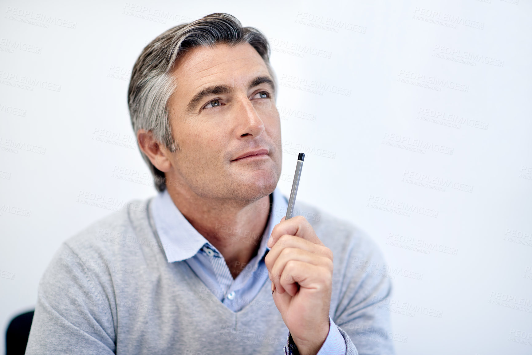 Buy stock photo Shot of a mature businessman holding his pen and looking thoughtful