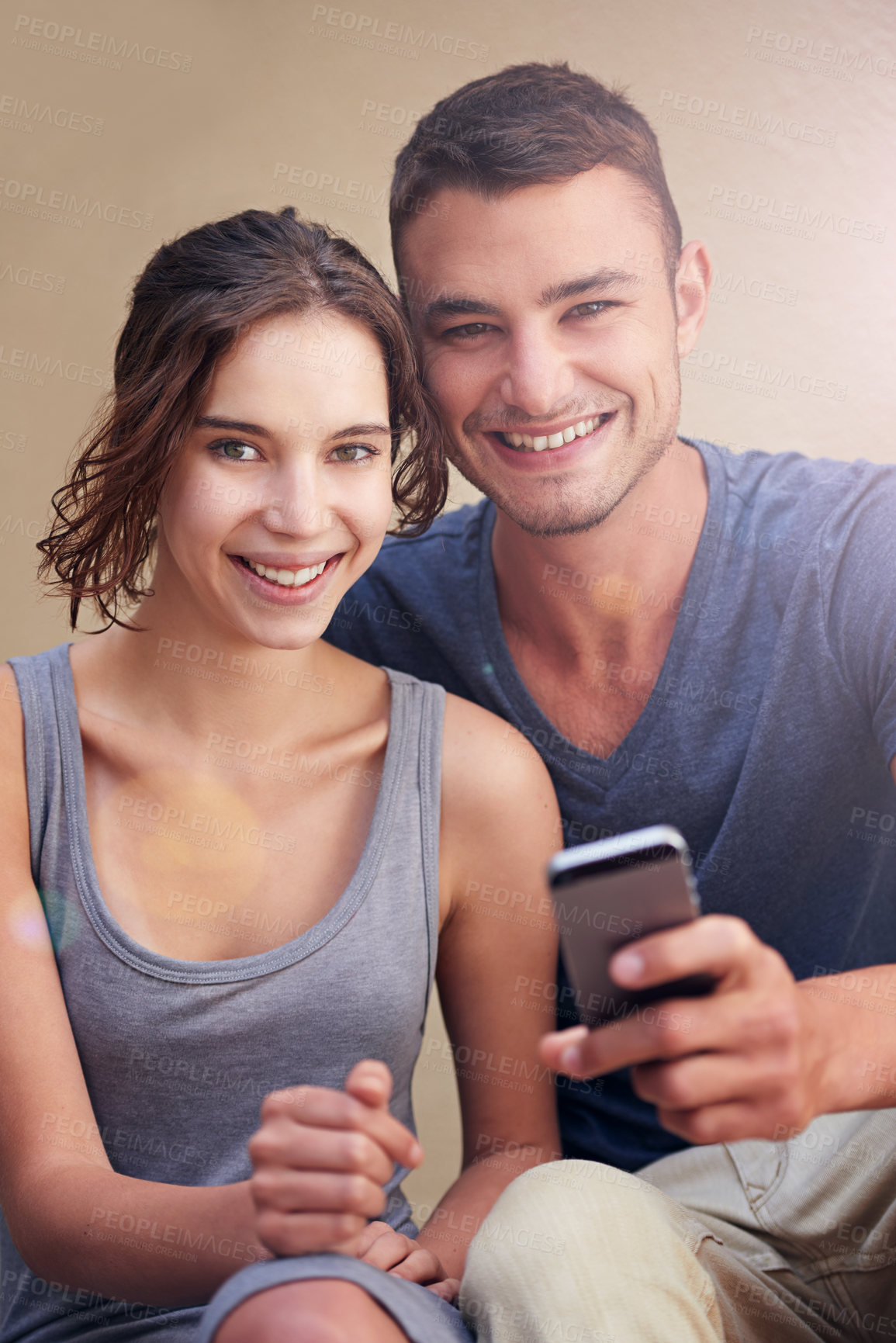 Buy stock photo Cropped shot of a young couple using a cellphone while sitting outside