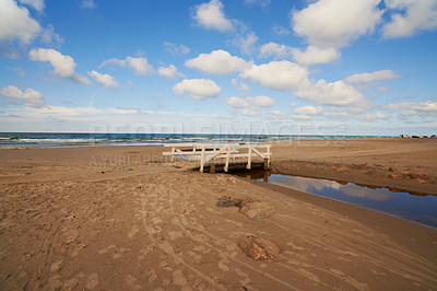 Buy stock photo Sand, ocean and seascape with small bridge for water crossing, environment care and horizon in Denmark. Nature, landscape and sea ecosystem at river mouth, human intervention and west coast beach