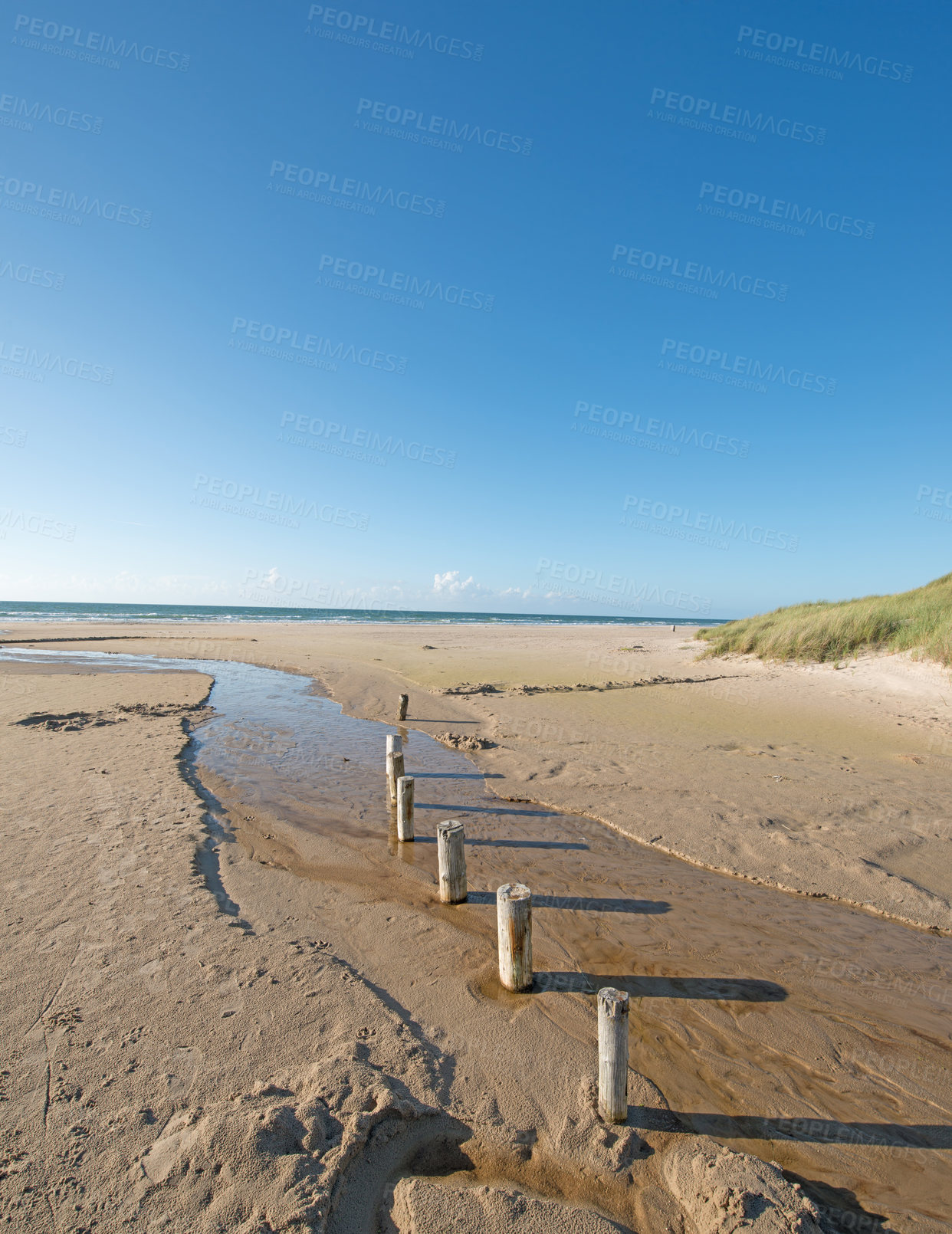 Buy stock photo Sand, ocean and seascape with small pillars for kayak docking, environment care and horizon in Denmark. Nature, landscape and sea ecosystem at river mouth, human intervention and west coast beach