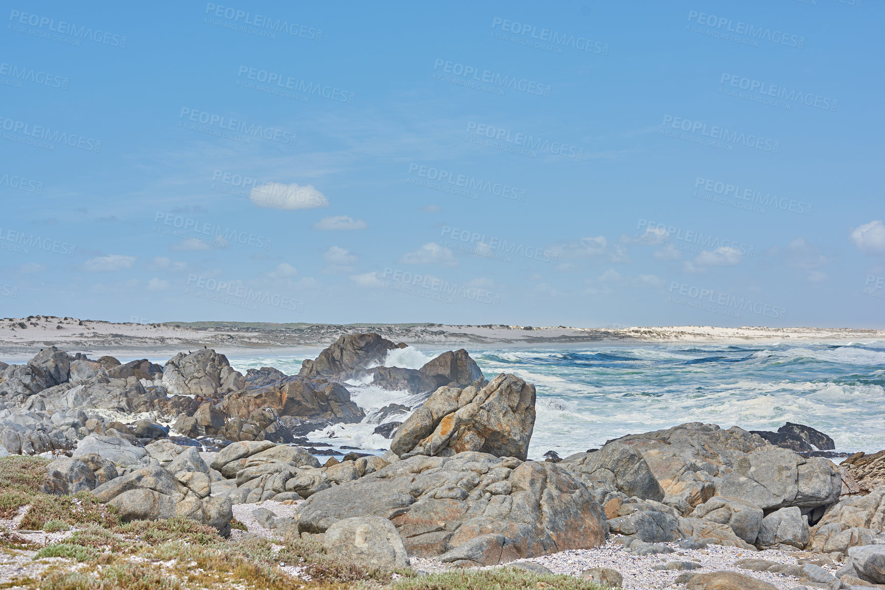 Buy stock photo A shallow rocky coastline in the Cape Province, South Africa. Ocean waves crashing on coastal rocks and boulders on a sunny summer day, blue clear skies, and a scenic tropical landscape beachfront