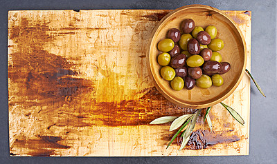 Buy stock photo Olives, organic and fruit on wood board or counter top for holiday, health and wellness in restaurant. Weight loss, brine and leaves in Greece for antioxidant, nutrition and fibre for vegetarian diet