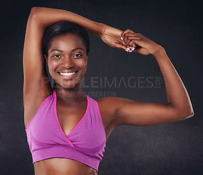 Buy stock photo Studio shot of a beautiful young woman stretching against a black background