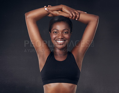 Buy stock photo Studio shot of a beautiful young woman stretching against a black background