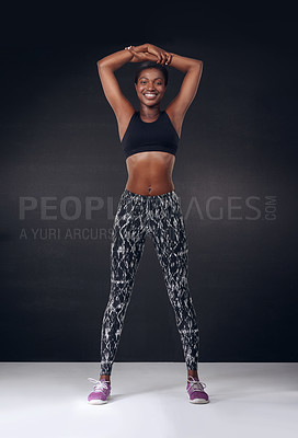 Buy stock photo Studio shot of a beautiful young woman stretching against a black background