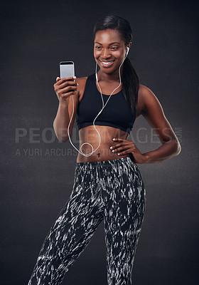 Buy stock photo Studio shot of a beautiful young woman listening to music during her workout against a black background