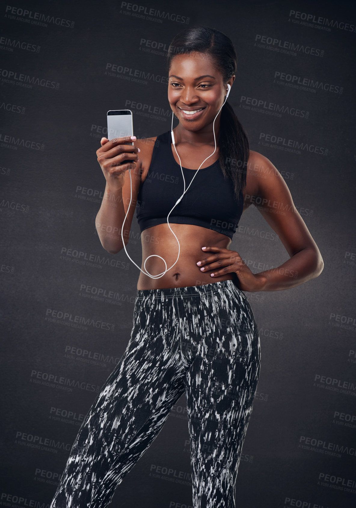 Buy stock photo Happy, black woman or fitness with phone or earphones for music on a dark studio background. African, female person or athlete with smile on mobile smartphone for sport app, podcast or audio playlist