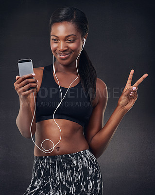 Buy stock photo Studio shot of a beautiful young woman using her phone during a workout against a black background