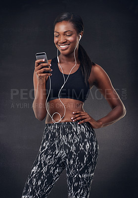 Buy stock photo Studio shot of a beautiful young woman listening to music during her workout against a black background