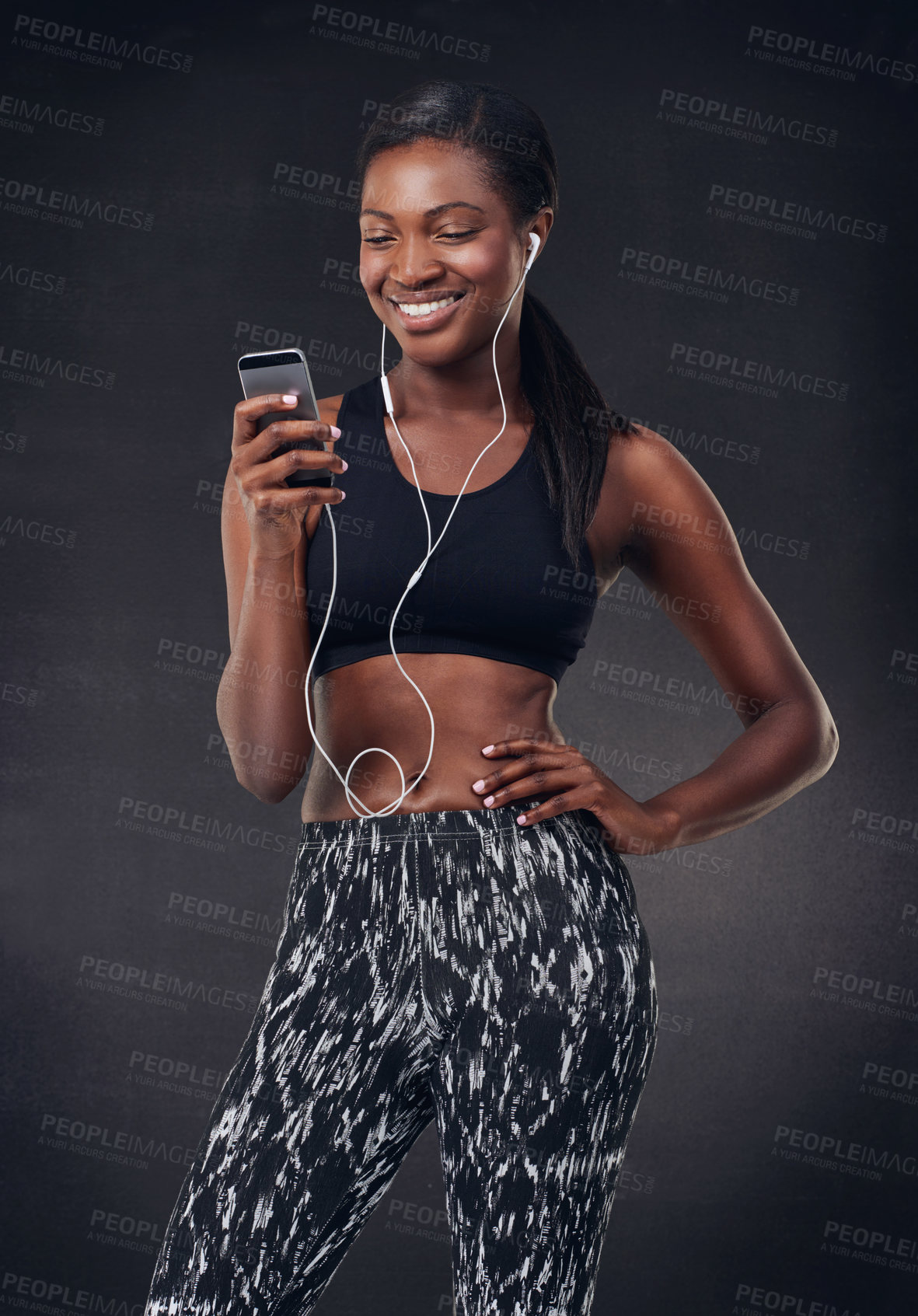 Buy stock photo Studio shot of a beautiful young woman listening to music during her workout against a black background