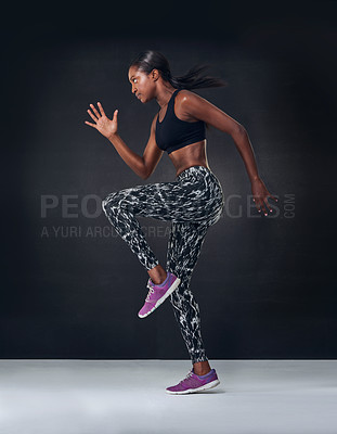 Buy stock photo Studio shot of a beautiful young woman jogging on the spot against a black background