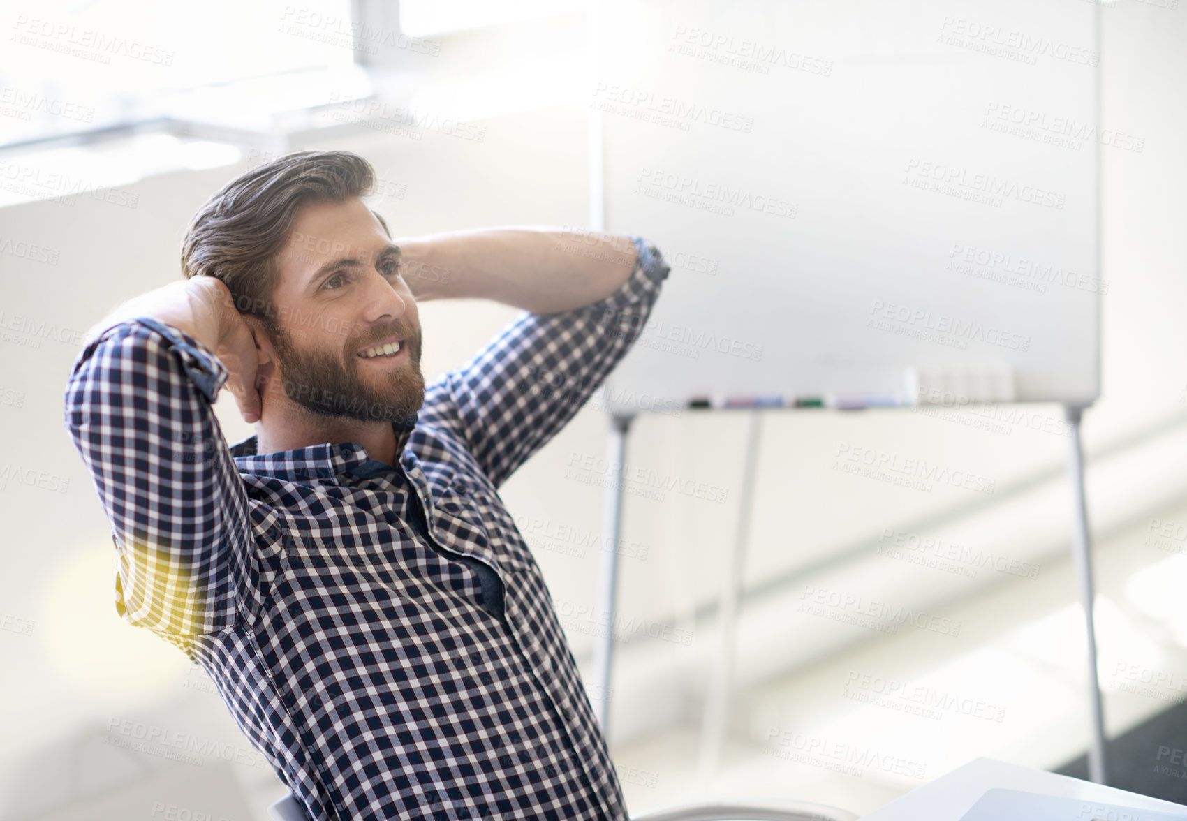 Buy stock photo Shot of handsome young man relaxing with his hands behind his head in an office