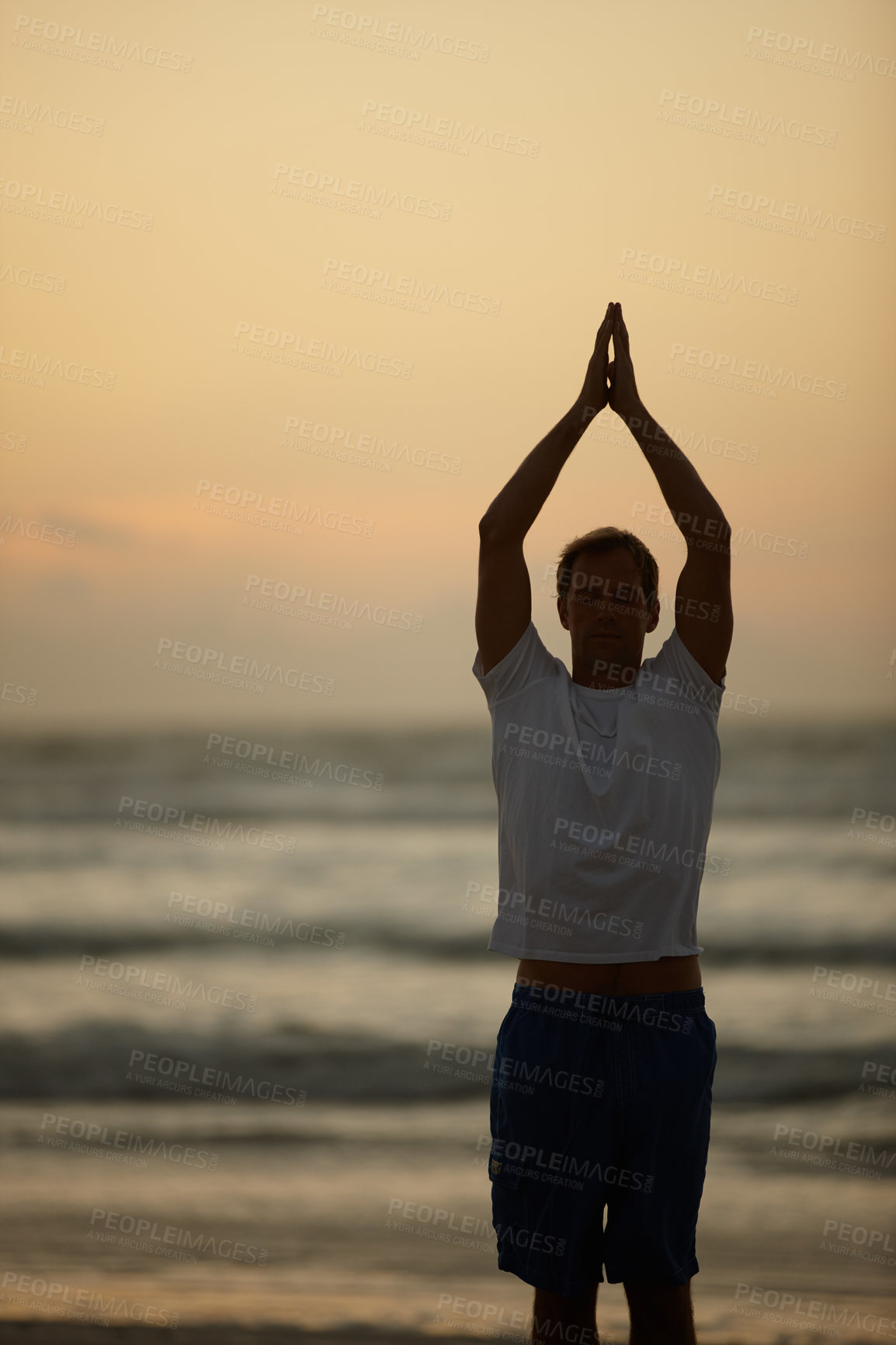 Buy stock photo Shot of a man doing yoga on the beach at sunset