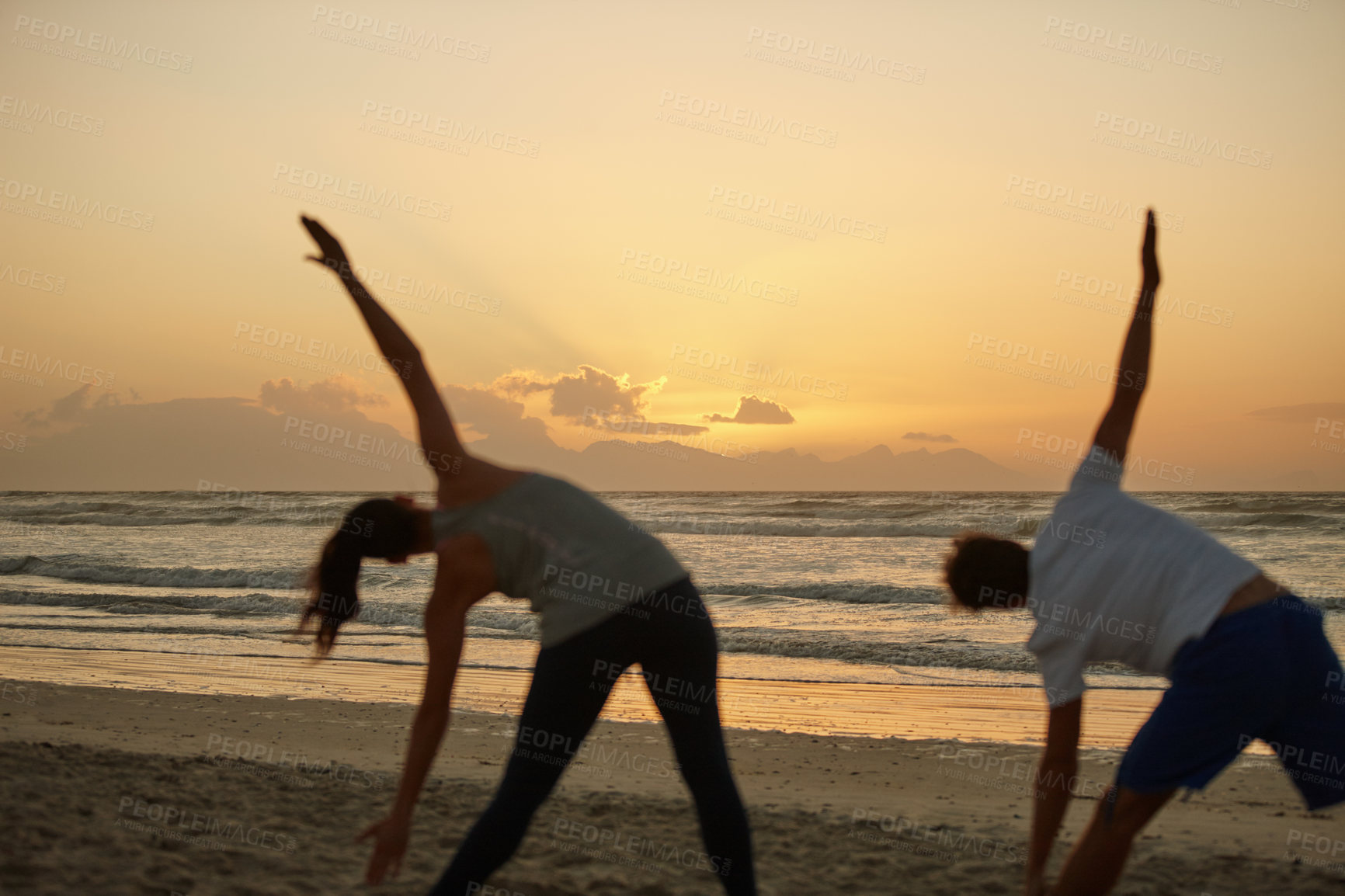 Buy stock photo Shot of a couple doing yoga on the beach at sunset