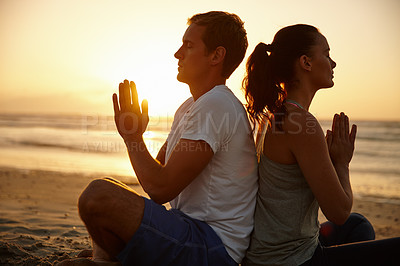 Buy stock photo Shot of a couple meditating on the beach at sunset