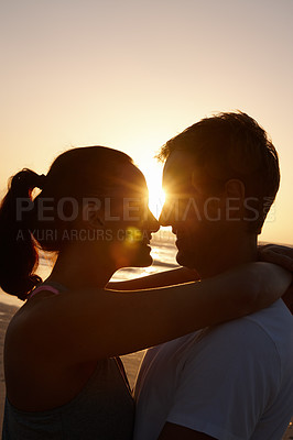 Buy stock photo Silhouette of a couple being romantic at the beach at sunset