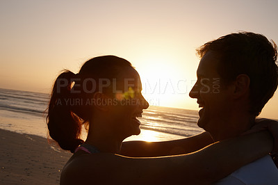 Buy stock photo Silhouette of a couple being romantic at the beach at sunset