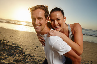 Buy stock photo Portrait of a man giving his girlfriend a piggyback ride at the beach